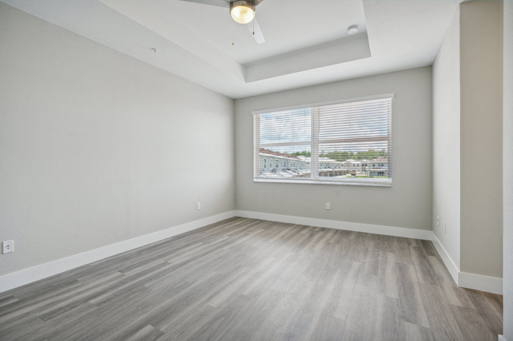 the living room of an apartment with wood floors and a large window
